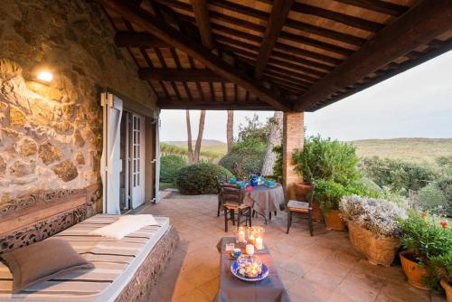 a patio with a table and a stone wall at Villa Renaissance: in Maremma, vicina al mare in Pescia Fiorentina