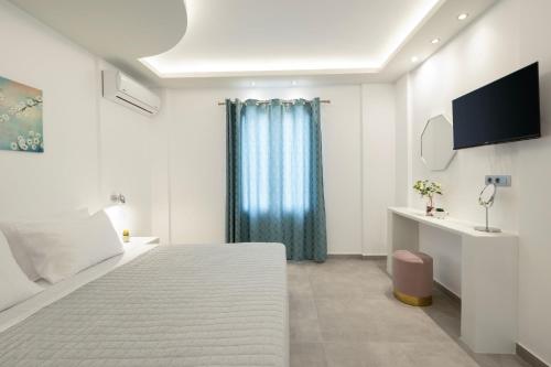 a white bedroom with a large bed and a tv at Windmillside Luxury Villas in Emporio Santorini