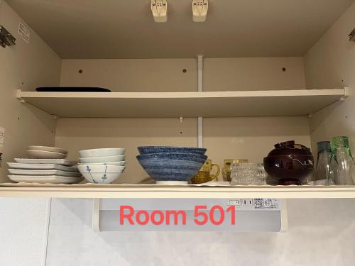 a shelf with bowls and plates on it with a room sign at SkyHotel Ryogoku 駅徒歩4分 in Tokyo