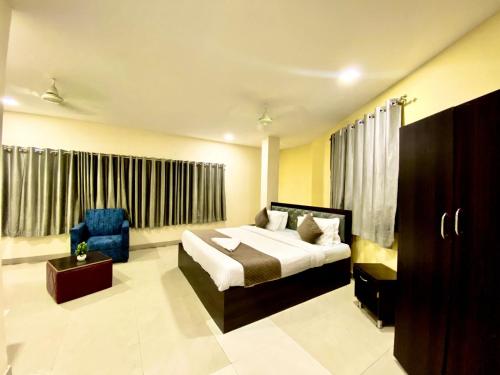 a bedroom with a bed and a blue chair at Hotel Sky Park in Shamshabad