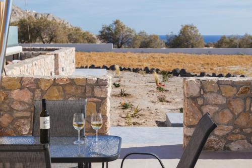 two glasses of wine on a table with a stone wall at Windmillside Luxury Villas in Emporio Santorini