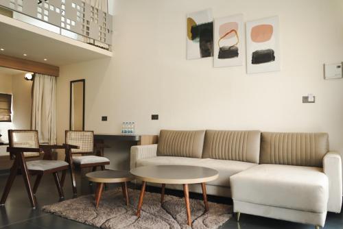 uma sala de estar com um sofá, uma mesa e cadeiras em Bir Valley Retreat em Bir