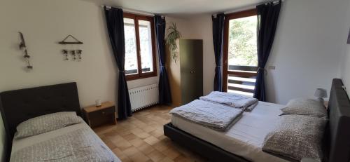 1 dormitorio con 2 camas y 2 ventanas en Casa Galet, en Pieve di Ledro