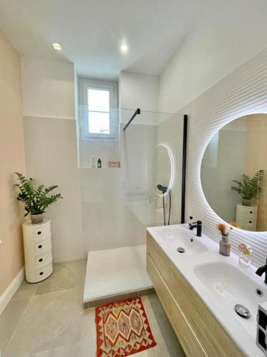 une salle de bain blanche avec un lavabo et un miroir dans l'établissement Palais Massenet -Exceptionnel 50m de la mer, à Nice