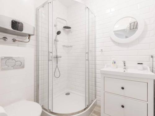 a white bathroom with a shower and a sink at Apartamenty Żarnowska in Żarnowska