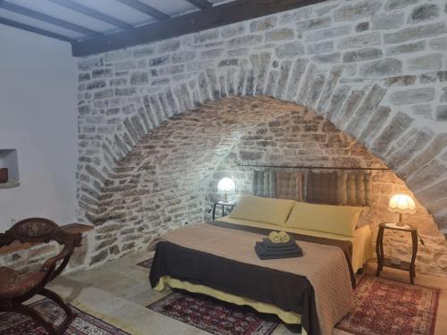 ケパロにあるVilla Olive Old Qeparoのレンガの壁にベッド1台が備わるベッドルーム1室