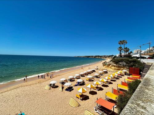 a beach with a bunch of umbrellas and the ocean at Apartamento Vista Mar a menos de 50m da praia. in Armação de Pêra