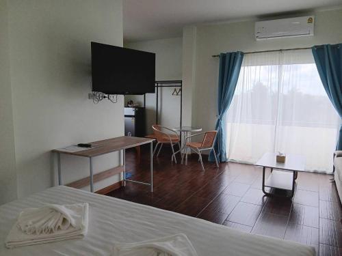 een hotelkamer met een bed, een tafel en een televisie bij โรงแรมนราพัตรา in Narathiwat