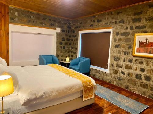 a bedroom with a bed and two blue chairs at Vintage Hut Dunga Gali in Abbottābād