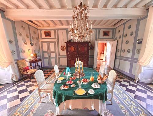 een eetkamer met een groene tafel en stoelen bij Château de Cadouzan in Saint-Dolay