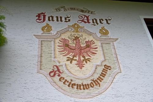 a sign on the side of a building with a coat of arms at Ferienwohnung Apartment Haus Ager in Thiersee