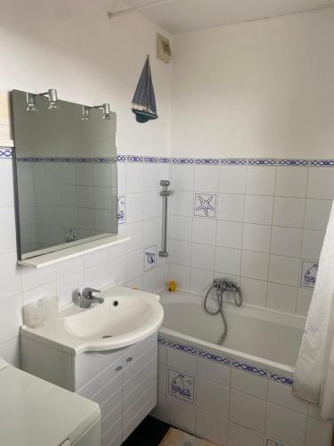 une salle de bain blanche avec un lavabo et une baignoire dans l'établissement La dérive - vue mer, à Wimereux