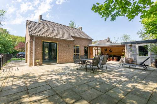 a patio with chairs and a table in front of a house at La casa Pacha Mama Sauna en Hottub in Ewijk
