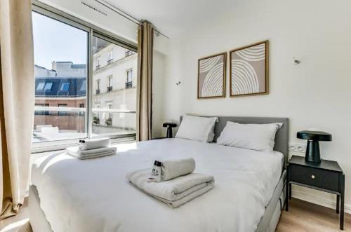 - une chambre avec un grand lit blanc et une grande fenêtre dans l'établissement Le Gentleman - Design & Lumineux - Business, à Paris