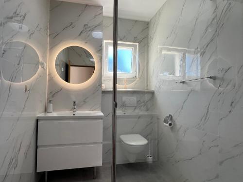 a white bathroom with a toilet and a mirror at Villa Milina Korčula in Vela Luka