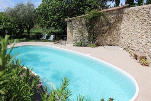 una gran piscina azul junto a una pared de piedra en Le Mazet, gîte des Lucioles en Provence, en Montségur-sur-Lauzon