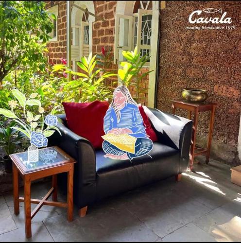 a couch with a painting of a woman sitting on it at Cavala The Seaside Resort in Baga