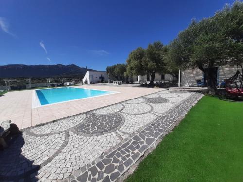 a backyard with a swimming pool and green grass at Borgo Rurale Cares in Dorgali