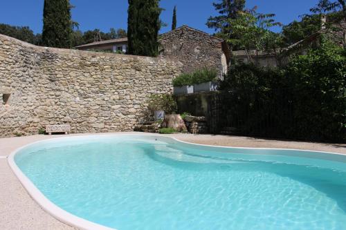 a large blue swimming pool next to a stone wall at Le Pigeonnier, gîte des Lucioles en Provence in Montségur-sur-Lauzon