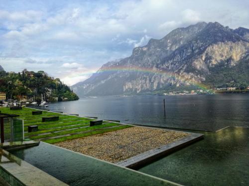 a rainbow over a lake with mountains in the background at Lungolago Malgrate in Malgrate