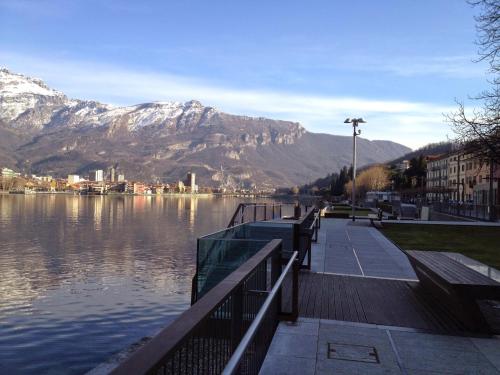 a walkway next to a body of water with mountains at Lungolago Malgrate in Malgrate