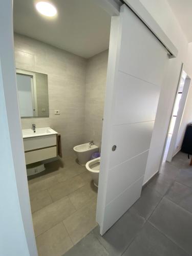 Baño blanco con aseo y lavamanos en Holiday Home & Rooftop Lounge, en Las Palmas de Gran Canaria