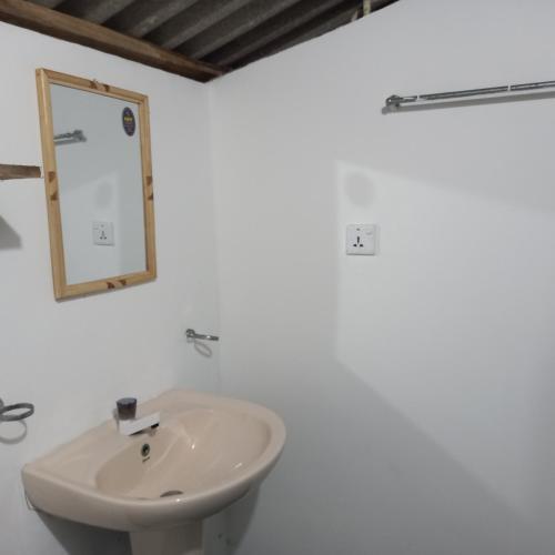 a white bathroom with a sink and a mirror at Bamboo Bay in Arugam Bay