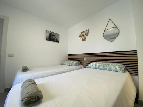two beds in a room with white walls at Holiday Home & Rooftop Lounge in Las Palmas de Gran Canaria