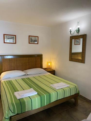 a bedroom with a green and white bed with a mirror at Villa Crimi in Vulcano