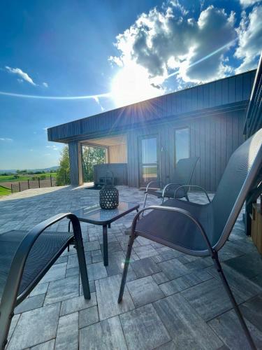 un patio con una mesa de cristal y sillas. en Stodoła Na Kresach - widokowy domek drewniany, całoroczny JACUZZI & SAUNA en Bodzentyn