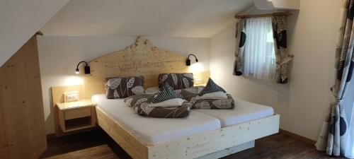 a bedroom with a white bed with a wooden headboard at Pension Fürhapter mit Bio- Bauernhof in Sankt Jakob in Defereggen
