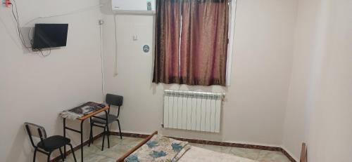 - un salon avec deux chaises et une télévision dans l'établissement Hostel 1 er novembre khenchela, à Khenchela