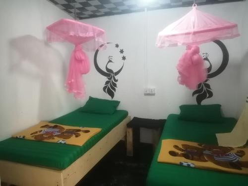 two beds in a room with pink and green at Cozy House Hostel in Ella