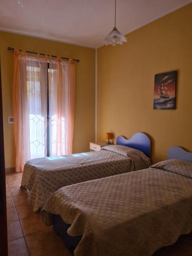 two beds in a room with a window at Casa in Centro in SantʼAntìoco