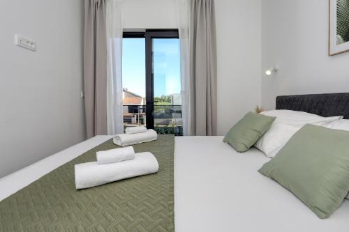 a bedroom with a white bed with two white chairs at Villa Cvit Mediterana with heated pool in Knežević