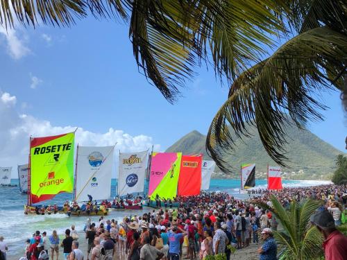 a crowd of people standing on a beach with flags at Face à la Plage avec Parking Sécurisé Appartement de Luxe ou Suite Privée avec Coin Petit Déj selon Disponibilité in Le Diamant