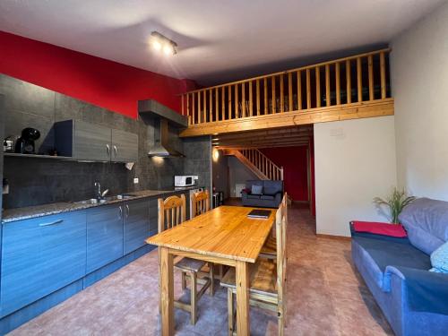 cocina y comedor con mesa de madera en una habitación en La Vall Apartaments Dúplex, en Sant Llorenç de Morunys
