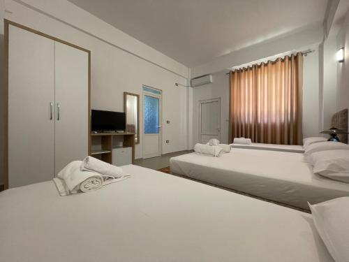 a white bedroom with two beds and a television at Villa Deart Berat in Berat