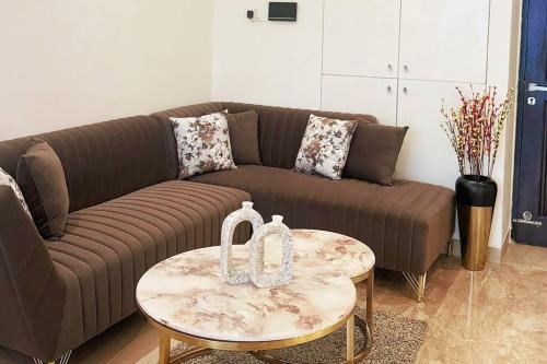 sala de estar con sofá marrón y mesa en SkyHigh Serenity. 2 Bhk Apartment. 0 Km From Delhi, en Noida