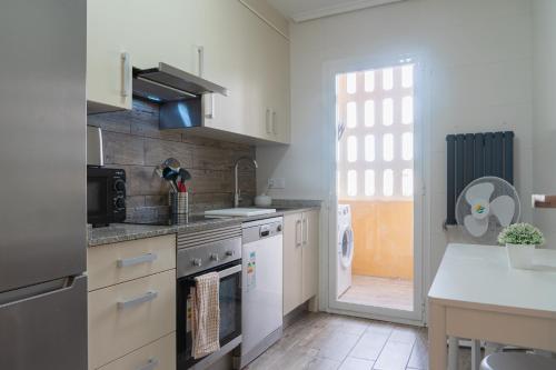 Il comprend une cuisine équipée d'appareils électroménagers blancs et une grande fenêtre. dans l'établissement CASA CHARROS, à Saragosse