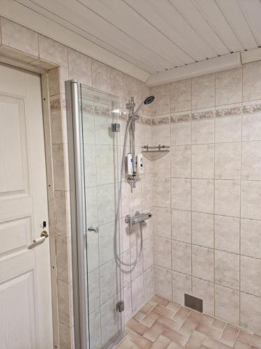 La salle de bains est pourvue d'une douche avec une porte en verre. dans l'établissement Villa Kataja, à Sjundeå