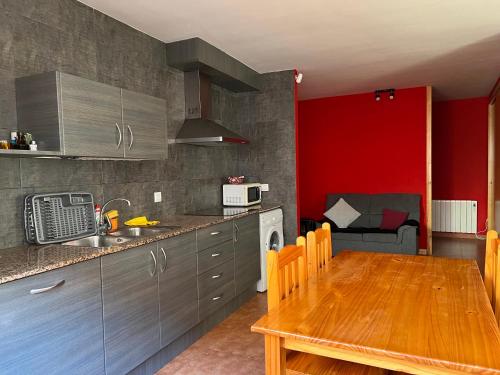 een keuken met een houten tafel en een rode muur bij La Vall Apartaments Loft in Sant Llorenc de Morunys