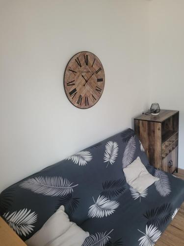 un canapé avec une horloge sur le mur et une horloge dans l'établissement Studio en plein cœur d’aubusson, à Aubusson