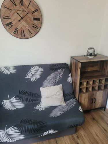 un canapé noir avec une horloge sur un mur dans l'établissement Studio en plein cœur d’aubusson, à Aubusson