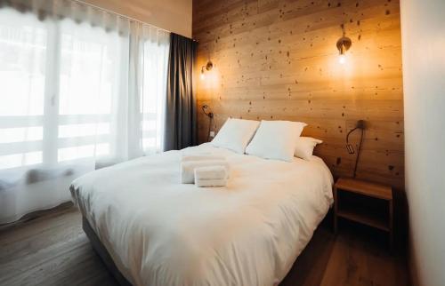 - une chambre avec un lit blanc et un mur en bois dans l'établissement Chalet familial de 6 chambres dominant Saint-Gervais classé 4 étoiles, à Saint-Gervais-les-Bains