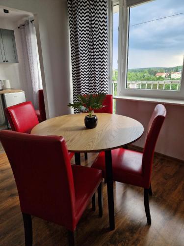 a dining room with a table and red chairs at Mieszkanie wakacyjne in Ruciane-Nida