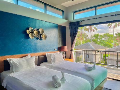 deux lits dans une chambre avec une grande fenêtre dans l'établissement ProudChan Boutique Resort, à Chanthaburi