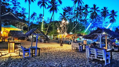 a group of people sitting in chairs on a beach at night at French Garden Regish Guest House in Trincomalee