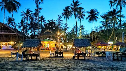 a group of tables and chairs on a beach at night at French Garden Regish Guest House in Trincomalee