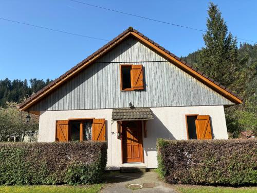 Maison blanche avec portes et fenêtres orange dans l'établissement Chalet Au fil de l'eau, à Gérardmer